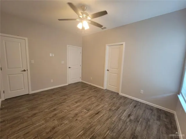 an empty room with wooden floor and fan