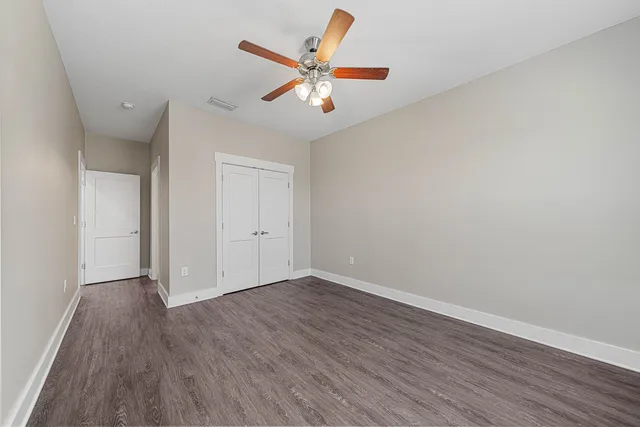 an empty room with wooden floor and ceiling fan