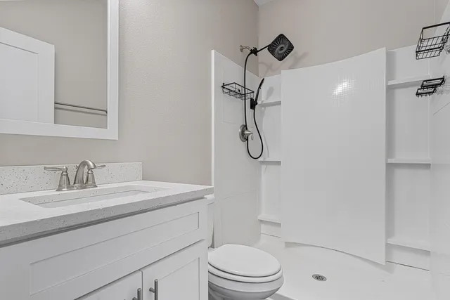 a bathroom with a sink toilet vanity and shower