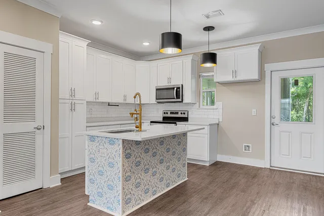 a kitchen with granite countertop a refrigerator a stove a microwave and white cabinets with wooden floor