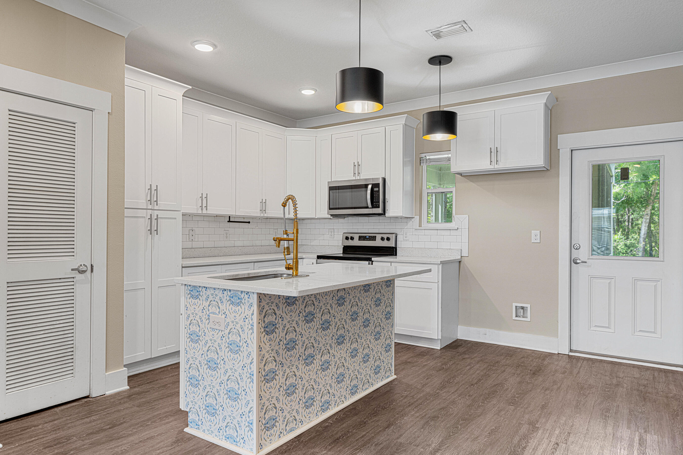 182 North Sand Palm Road Freeport, FL 32439 - Photo 5 of 38 a kitchen with granite countertop a refrigerator a stove a microwave and white cabinets with wooden floor