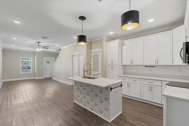 a kitchen with a sink chandelier and wooden floor