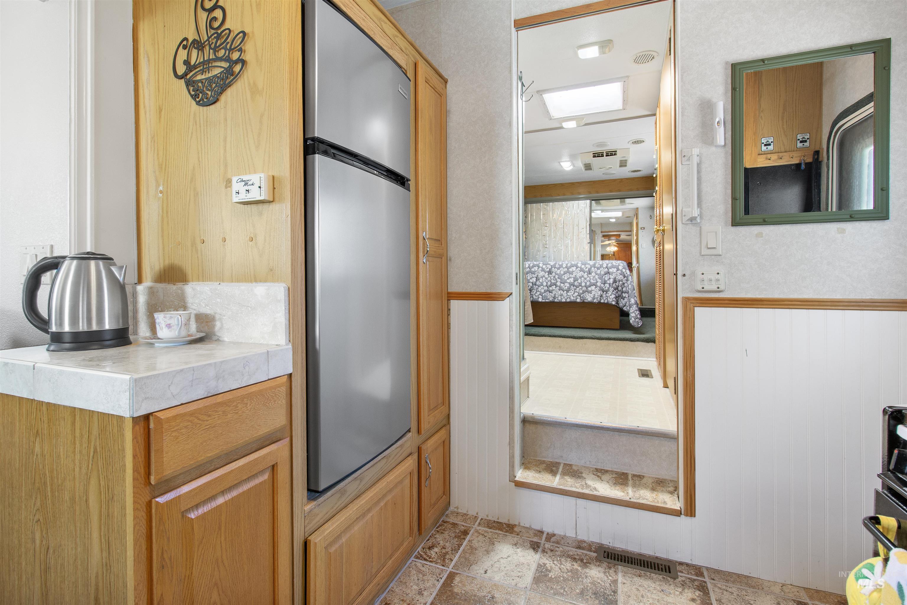 106 West Magic Road Shoshone, ID 83352 - Photo 21 of 45 Compact kitchen area featuring wood-finish cabinetry, a stainless-steel refrigerator, and light-colored countertops with a matching backsplash