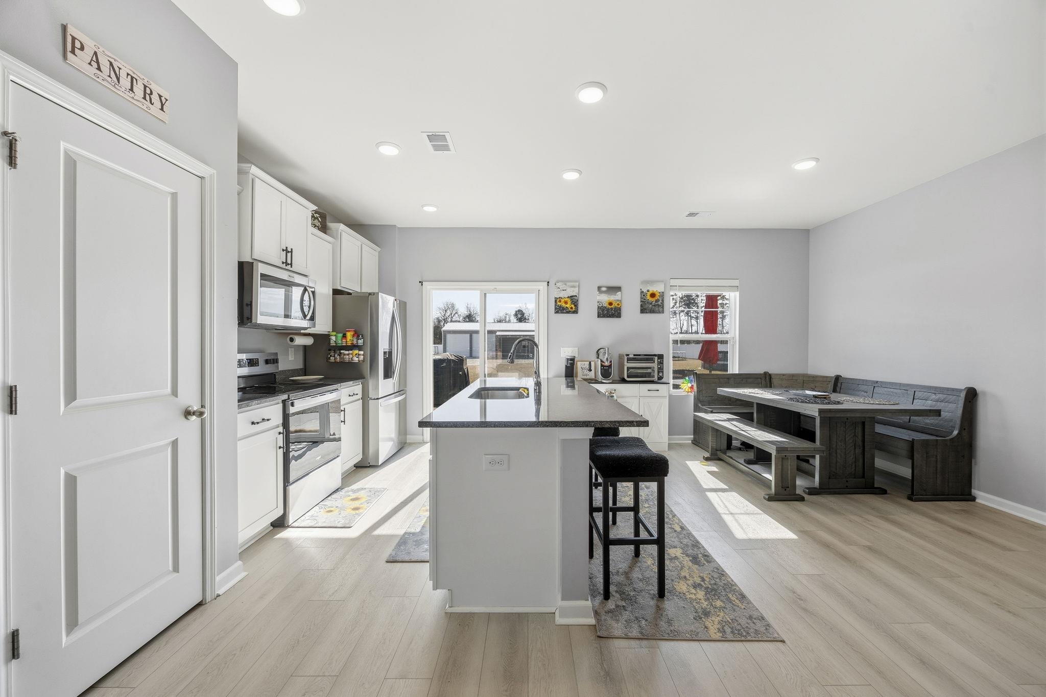 1010 Log Cabin Road Loris, SC 29569 - Photo 11 of 40 Kitchen with white cabinets, a kitchen island with sink, stainless steel appliances, a kitchen breakfast bar, and light wood-type flooring