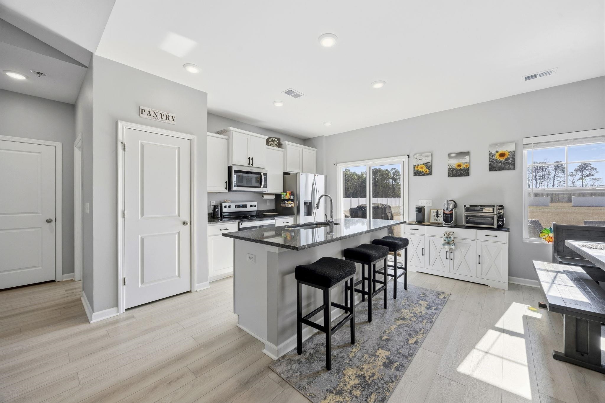 1010 Log Cabin Road Loris, SC 29569 - Photo 12 of 40 Kitchen with white cabinets, a kitchen breakfast bar, light wood-type flooring, stainless steel appliances, and a center island with sink