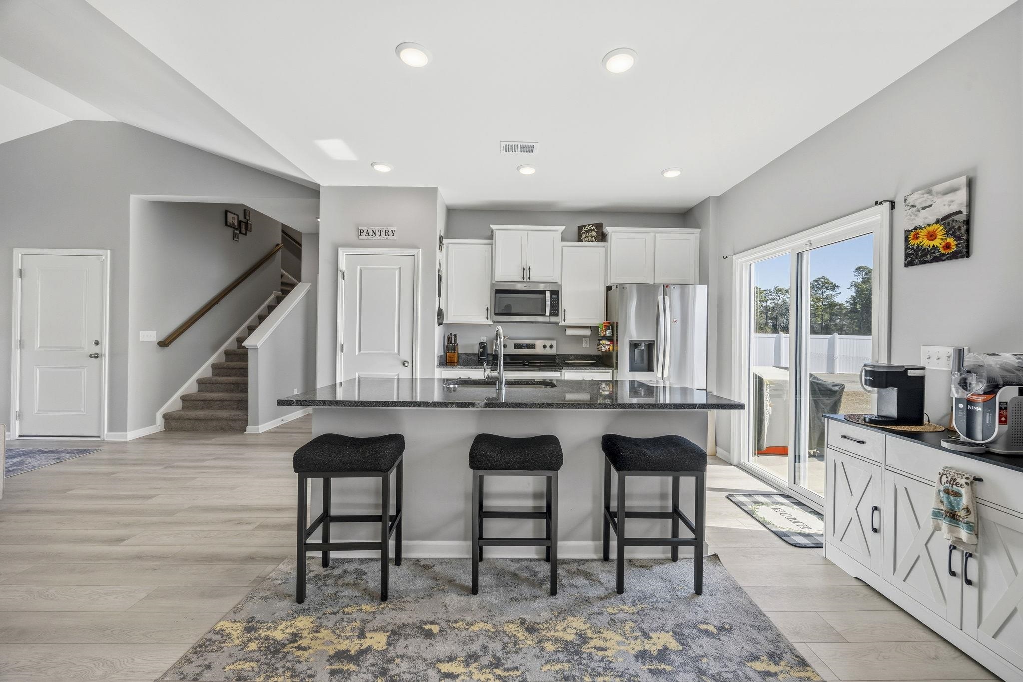 1010 Log Cabin Road Loris, SC 29569 - Photo 13 of 40 Kitchen featuring white cabinets, a breakfast bar, dark stone countertops, an island with sink, and stainless steel appliances