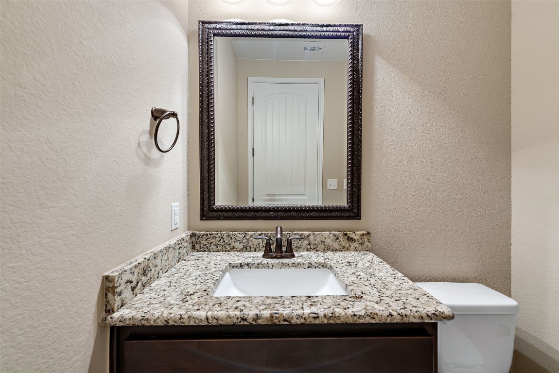 2000 Manada Trail Leander, TX 78641 - Photo 32 of 36 A well-appointed bathroom features a single vanity with granite countertops and a framed mirror.