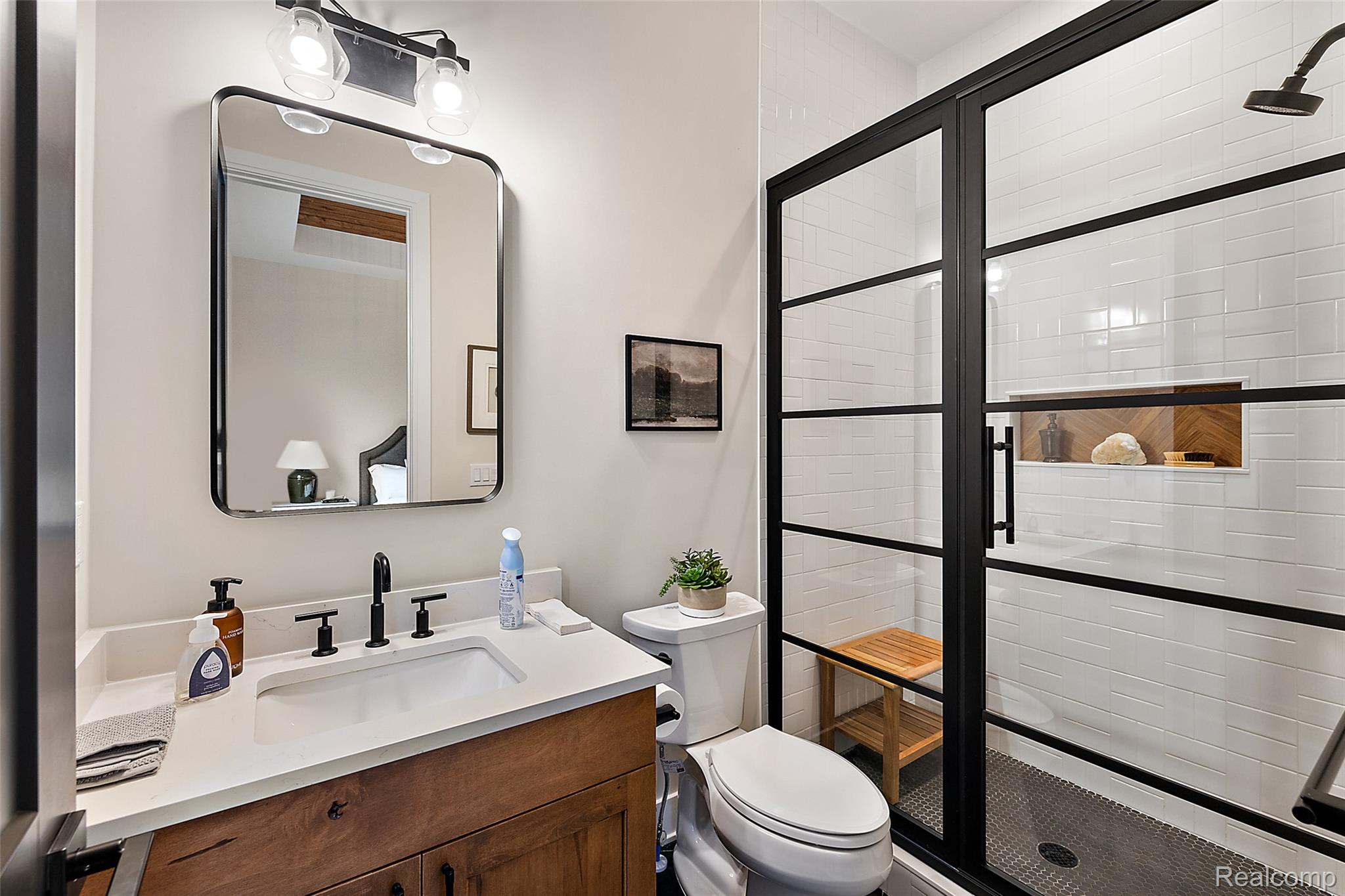 70413 Renata Court Romeo, MI 48065 - Photo 44 of 53 White subway-tiled shower with black-framed glass enclosure, built-in shelving, and dark mosaic tile flooring