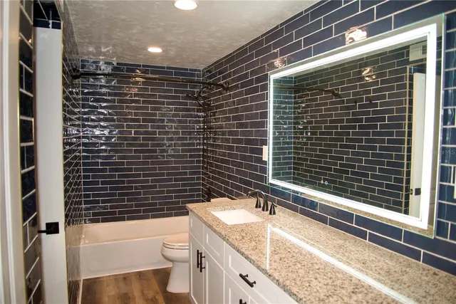 a bathroom with a granite countertop toilet a sink and mirror