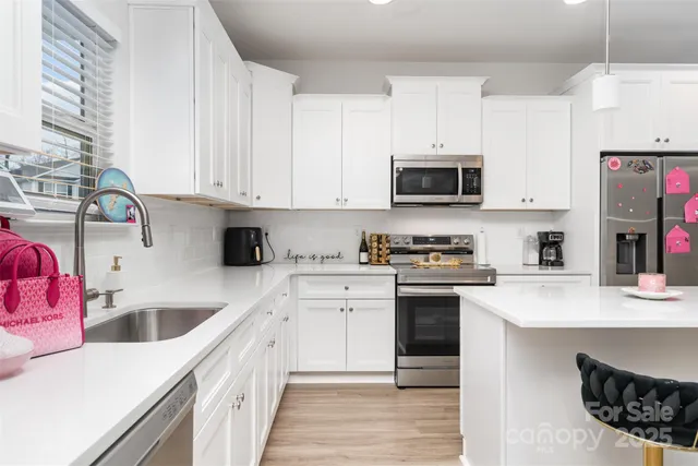 a kitchen with stainless steel appliances granite countertop a sink dishwasher stove and white cabinets with wooden floor