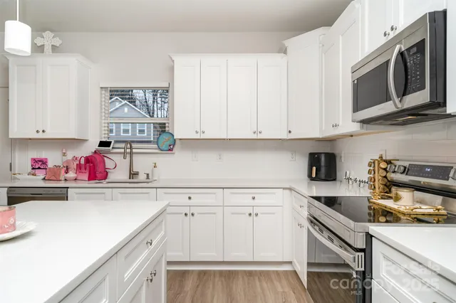 a kitchen with stainless steel appliances granite countertop a sink dishwasher stove and microwave with wooden cabinets