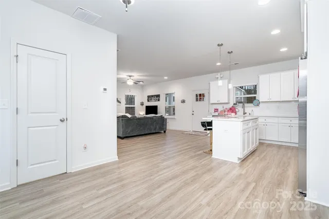 a kitchen with kitchen island wooden floors white cabinets and refrigerator