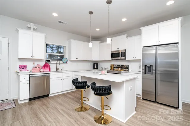a kitchen with kitchen island a white counter top space cabinets and stainless steel appliances