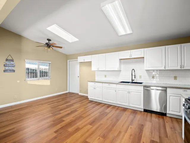 a large kitchen with cabinets wooden floor and stainless steel appliances