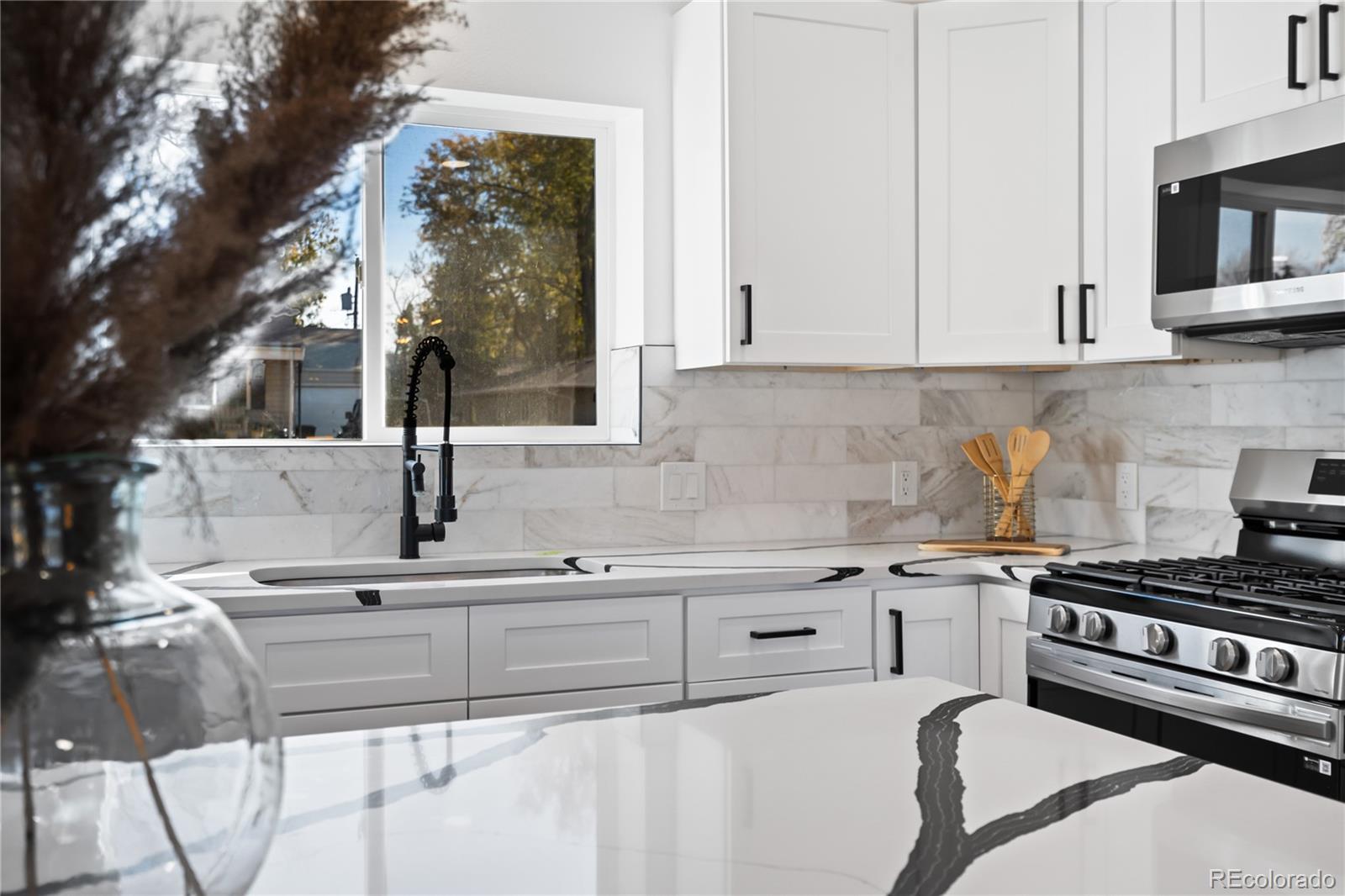 7921 Raleigh Street Westminster, CO 80030 - Photo 15 of 43 a kitchen with stainless steel appliances kitchen island granite countertop a sink stove and cabinets
