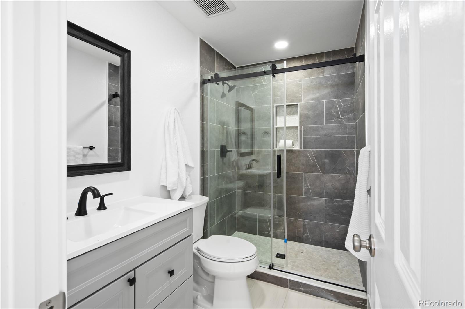 7921 Raleigh Street Westminster, CO 80030 - Photo 24 of 43 a bathroom with a shower sink vanity mirror and toilet