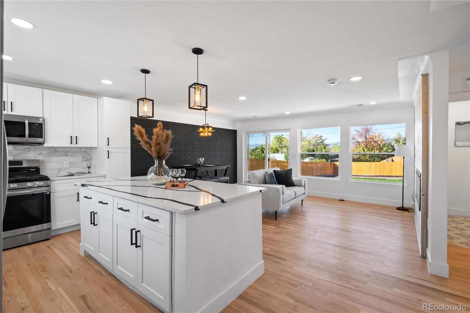 7921 Raleigh Street Westminster, CO 80030 - Photo 5 of 43 a view of a kitchen with kitchen island granite countertop a stove and a view of living room