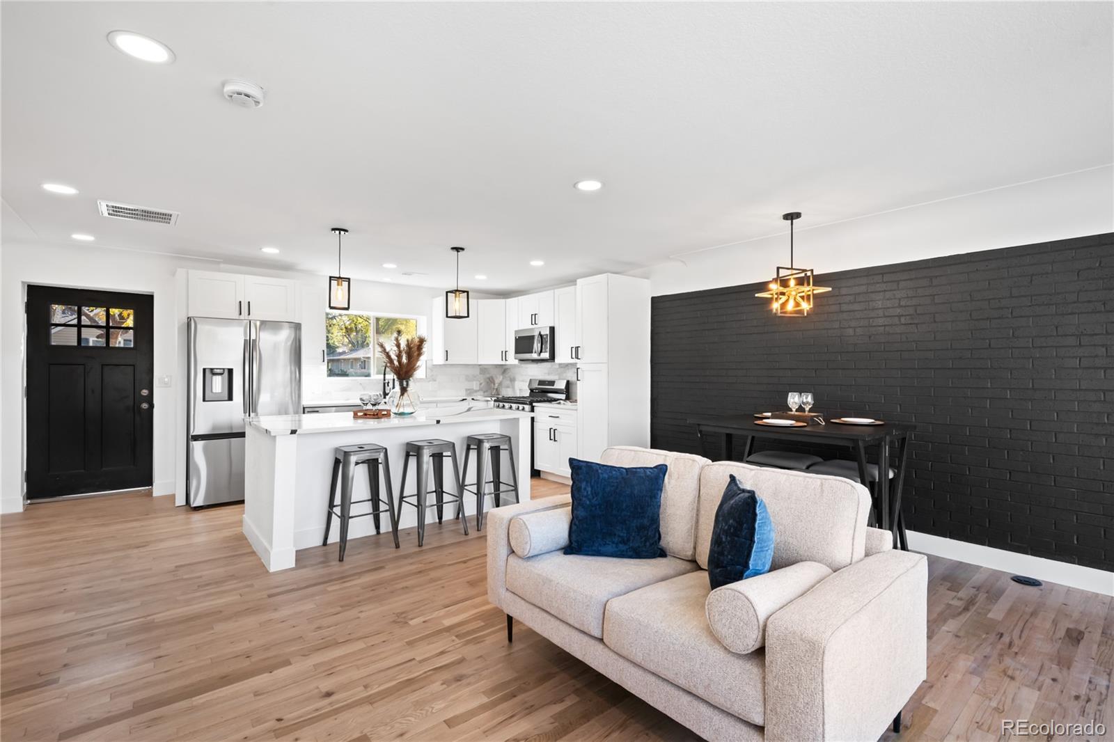 7921 Raleigh Street Westminster, CO 80030 - Photo 8 of 43 a living room with stainless steel appliances kitchen island granite countertop furniture and a wooden floor