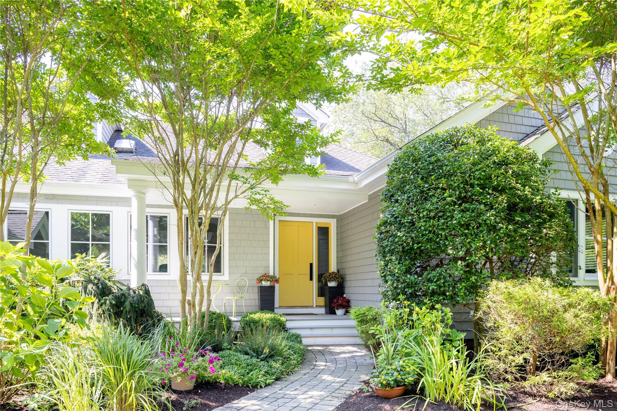 a front view of a house with plants and trees