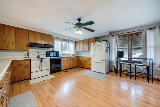 a kitchen with granite countertop a stove a sink dishwasher a refrigerator and a dining table with wooden floor