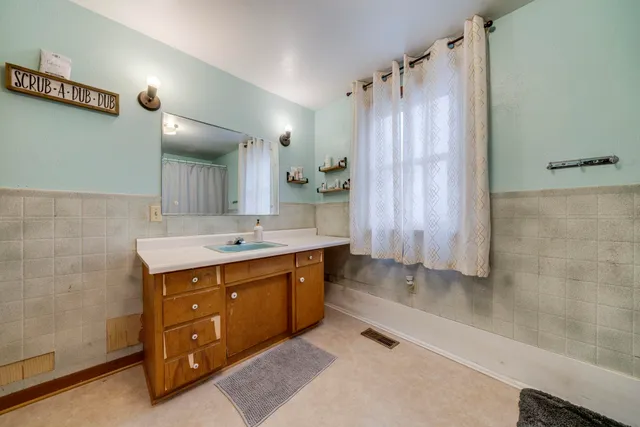a spacious bathroom with a double vanity sink a large mirror and shower