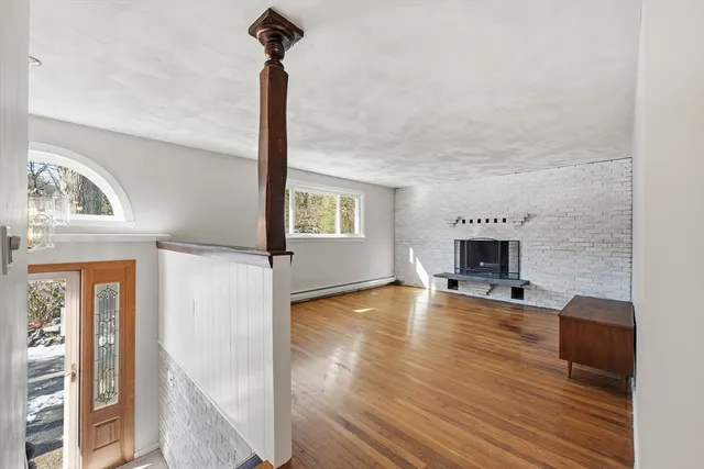 a view of empty room with fireplace and wooden floor