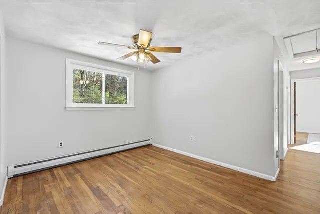 an empty room with wooden floor fan and windows