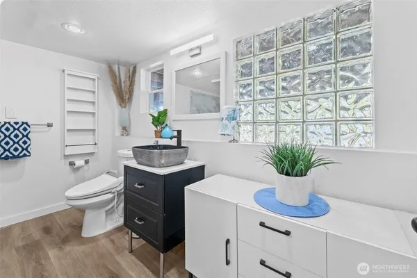 a bathroom with a sink a mirror a toilet and a window