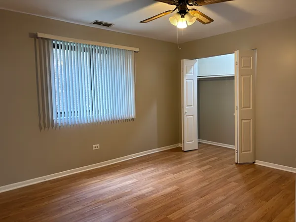 an empty room with wooden floor fan and windows