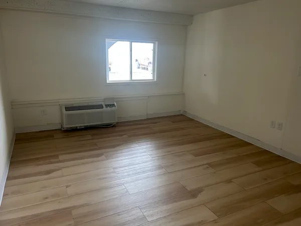 an empty room with wooden floor and windows