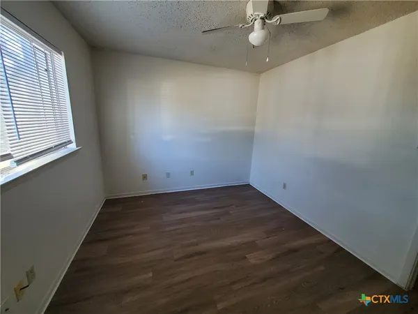 an empty room with a ceiling fan and window