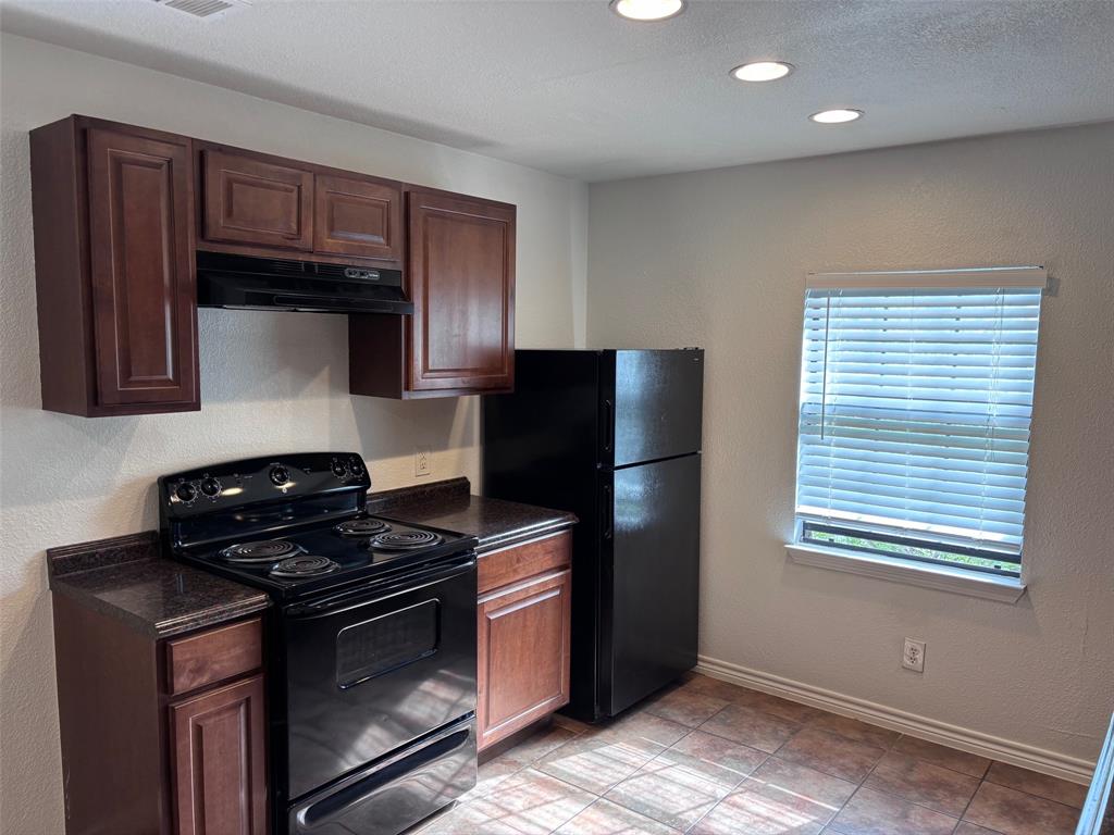 5003 Bryan Street, Unit 8 Dallas, TX 75206 - Photo 4 of 13 a kitchen with granite countertop wooden cabinets and a stove top oven