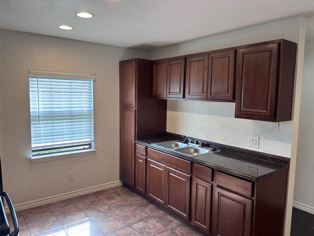 5003 Bryan Street, Unit 8 Dallas, TX 75206 - Photo 5 of 13 a kitchen with granite countertop wooden cabinets and a stove top oven