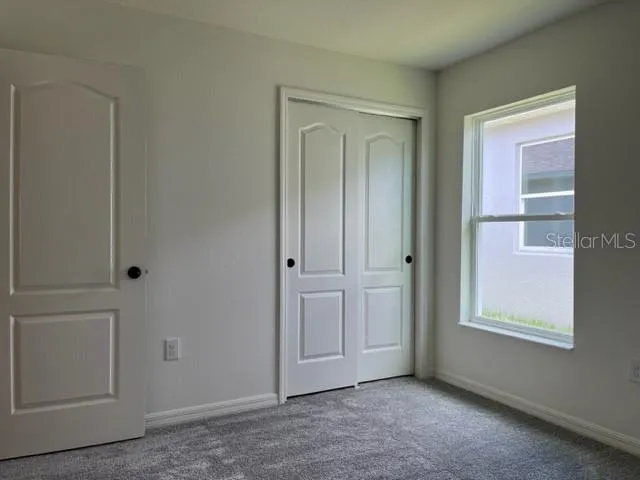 a view of an empty room with closet and a window