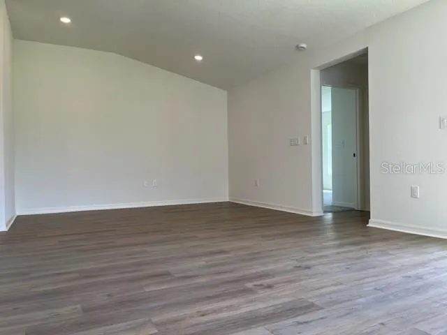 a view of an empty room with wooden floor and closet