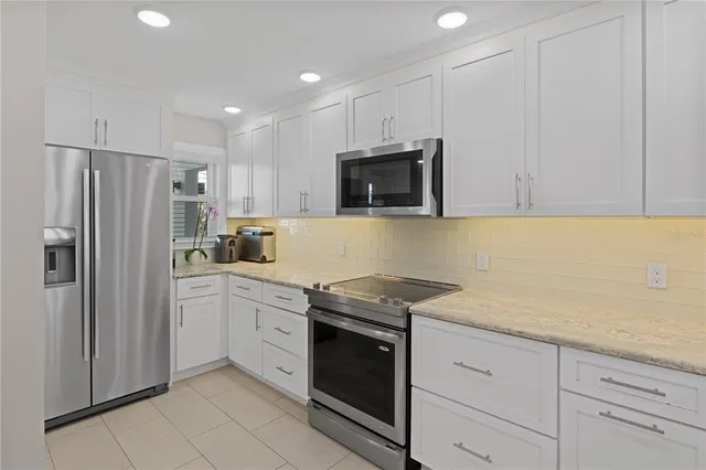 a kitchen with granite countertop white cabinets and stainless steel appliances
