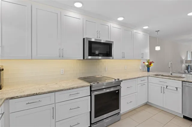 a kitchen with granite countertop white cabinets stainless steel appliances and a sink
