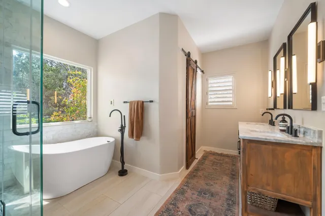 a bathroom with a tub a sink a mirror and a window