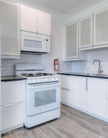 a kitchen with granite countertop white cabinets and white appliances