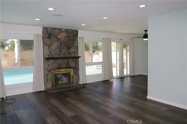 an empty room with wooden floor fireplace and windows