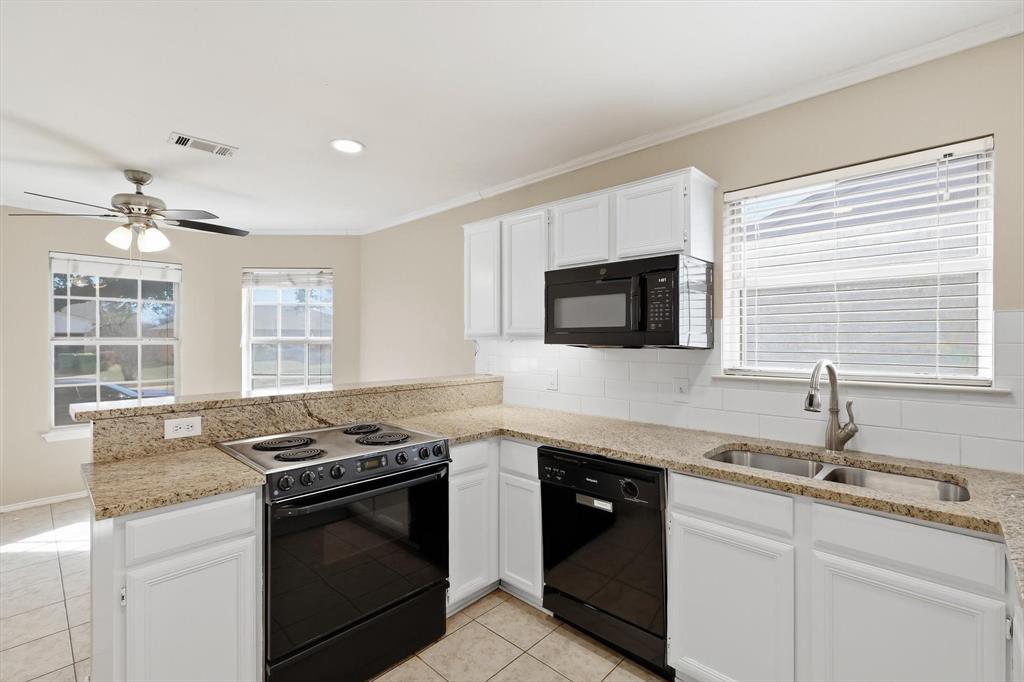 7733 Liz Lane Watauga, TX 76148 - Photo 9 of 27 Kitchen featuring black appliances, a peninsula, tasteful backsplash, white cabinetry, and plenty of natural light