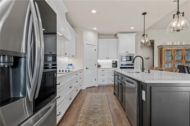 a kitchen with stainless steel appliances granite countertop a sink and a refrigerator