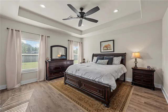 a bedroom with a bed and a large window with wooden floor