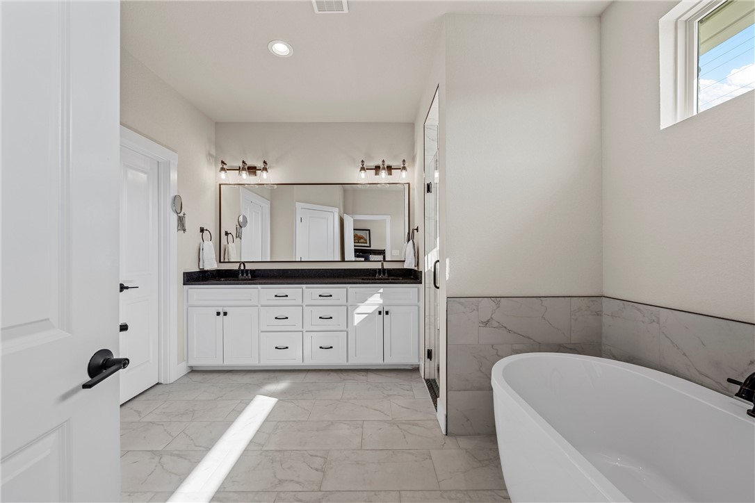 848 Gallant Fox Hewitt, TX 76643 - Photo 18 of 32 a bathroom with a bathtub sink and mirror