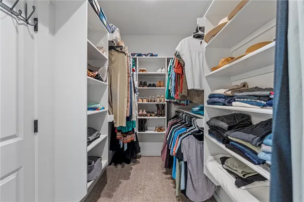 a view of walk in closet with clothes and shoes