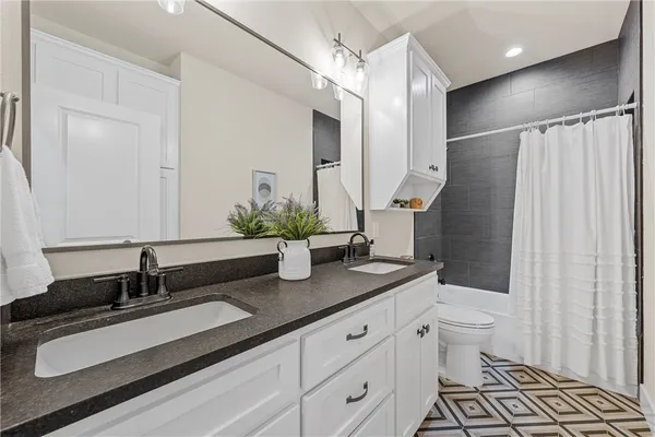a bathroom with a granite countertop sink a toilet a mirror and shower