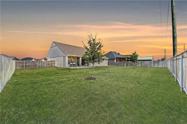 a view of a house with a big yard plants and large trees
