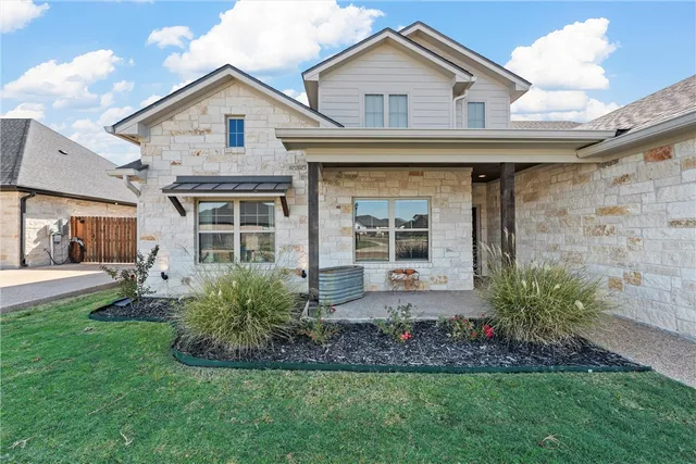 a front view of a house with a garden and plants