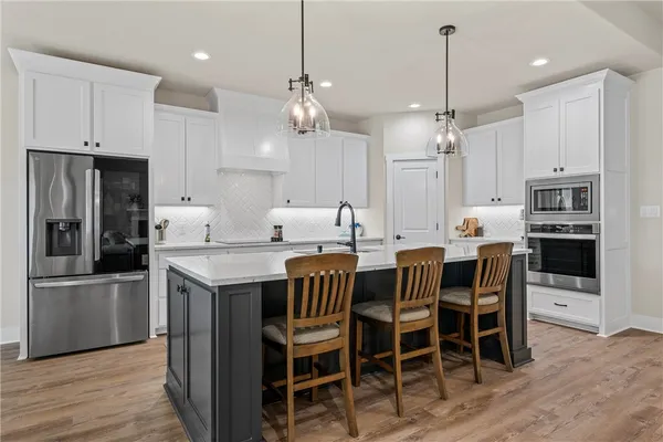a kitchen with stainless steel appliances kitchen island granite countertop a dining table chairs and white cabinets