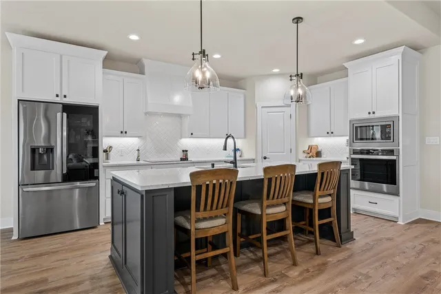 a kitchen with stainless steel appliances kitchen island granite countertop a dining table chairs and white cabinets